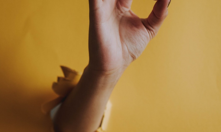 woman showing okay symbol through hole in the wall