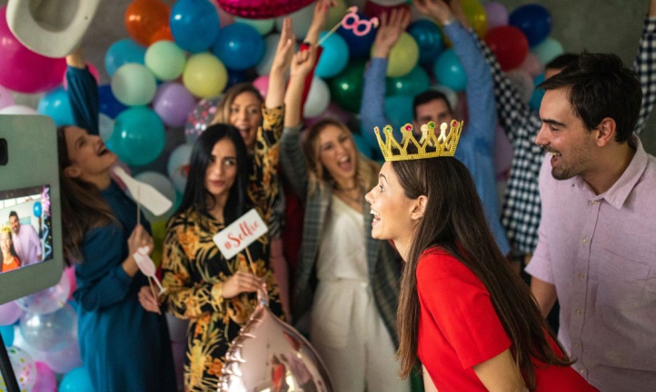 A couple taking photos at a digital photo booth surrounded by friends