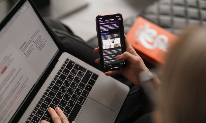 A woman email marketing with a cellphone and a laptop