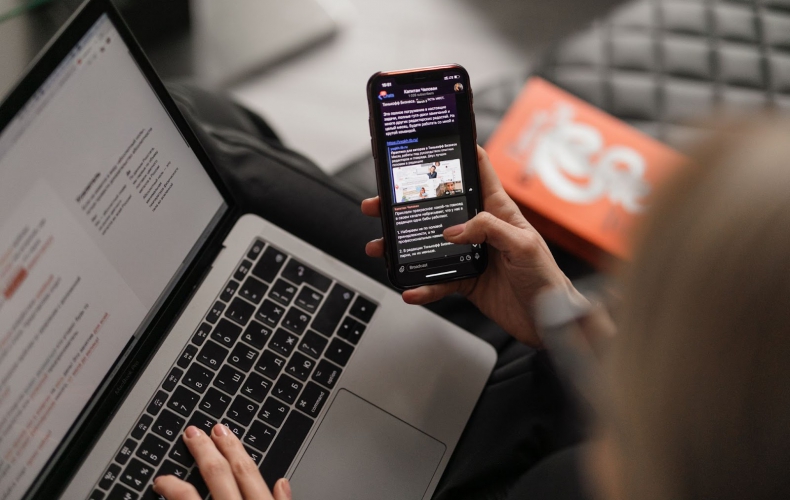 A woman email marketing with a cellphone and a laptop